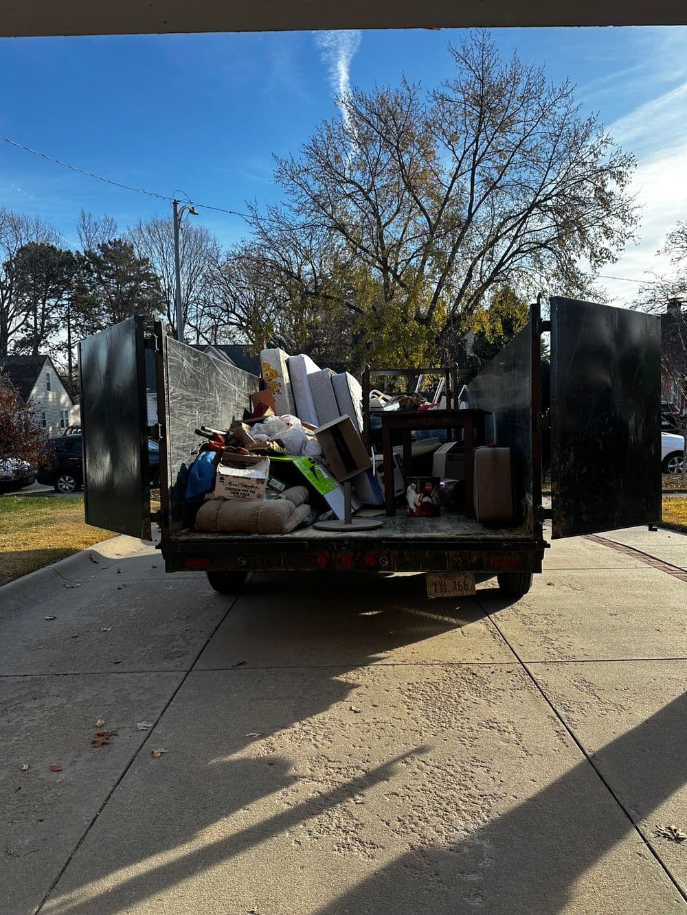 Dump truck loaded with various items and debris, parked on a residential driveway.