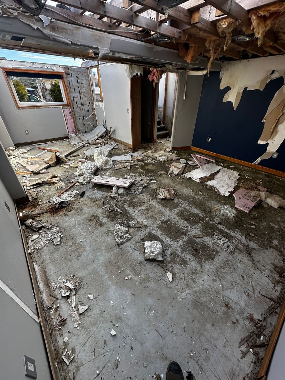 Dilapidated interior of a house with debris and exposed walls on the floor.
