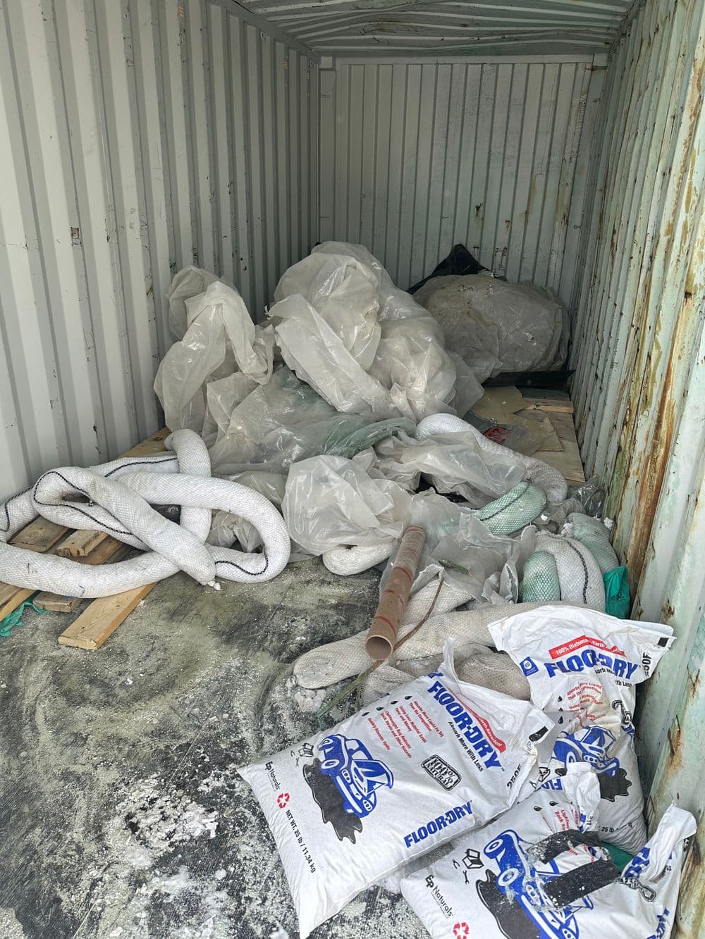 Cluttered storage container with plastic sheeting and bags of floor drying material.