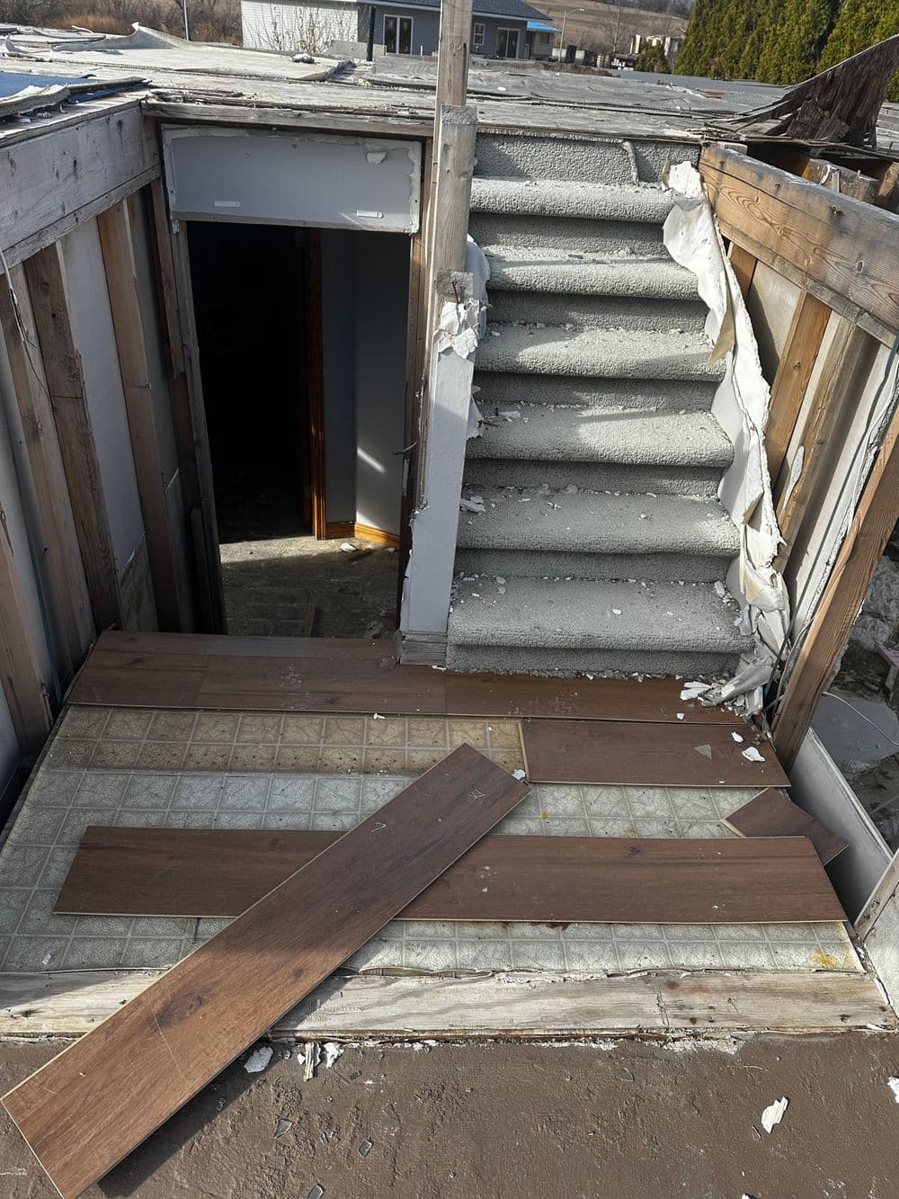 Staircase and damaged flooring in an abandoned building interior.